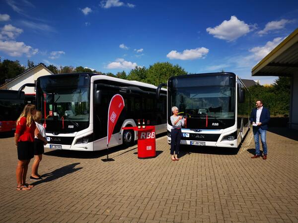 Landrätin und Samtgemeindebürgermeister stehen vor neuen Bussen.