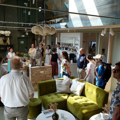 Eine Gruppe Menschen steht in einer Scheune. Die Scheune ist zu einem Coworking-Space ausgebaut worden.