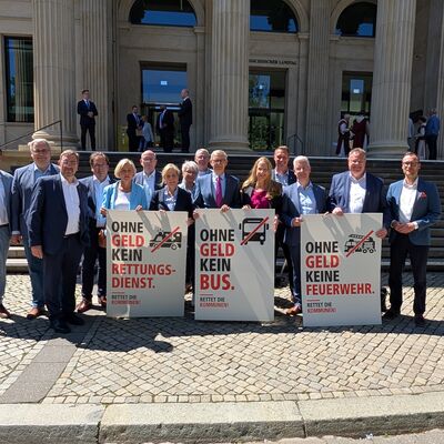 Ein Gruppenfoto von Landr�tinnen und Landr�ten aus Niedersachsen. Sie stehen vor dem Landtag in Hannover und halten drei Demonstrationsschilder in die Kamera.
