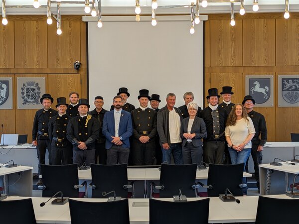 Eine Gruppe von Menschen. Viele davon sind Schornsteinfeger. Sie sind in traditioneller schwarzer Kleidung mit Zylinder.