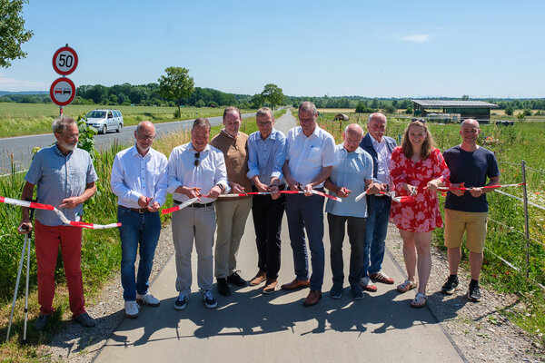 Gruppe von Menschen auf dem neuen Radweg von Cremlingen nach Hordorf. Sie halten gemeinsam ein Band, welches sie zur Er�ffnung des Weges zerschneiden.