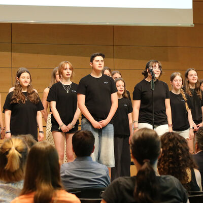 Kinder und Jugendliche stehen in schwarzen Shirt auf einer B�hne und singen.