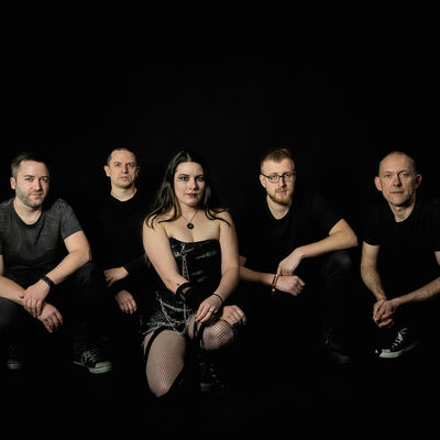 Schwarzer Hintergrund. Ein Gruppenfoto von knieenden Menschen in schwarzer Kleidung.