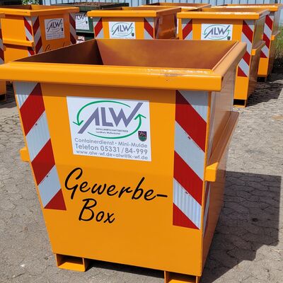 Orangefarbener Abfallcontainer im Vordergrund. Im Hintergrund mehrere weitere orangene Container. An den Seiten rot-wei� Leuchtsteifen. Sie stehen auf Asphaltboden.