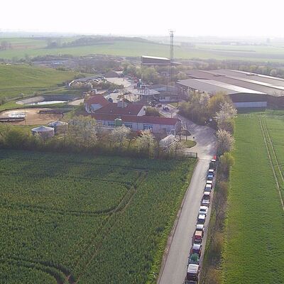 Luftbildaufnahme. Wiesen und Felder. In der Mitte mehrere Geb�ude mit roten oder silbernen D�chern.