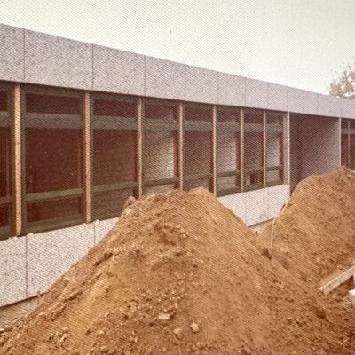 Ein Haufen Sand vor einem Schulgeb&auml;ude.