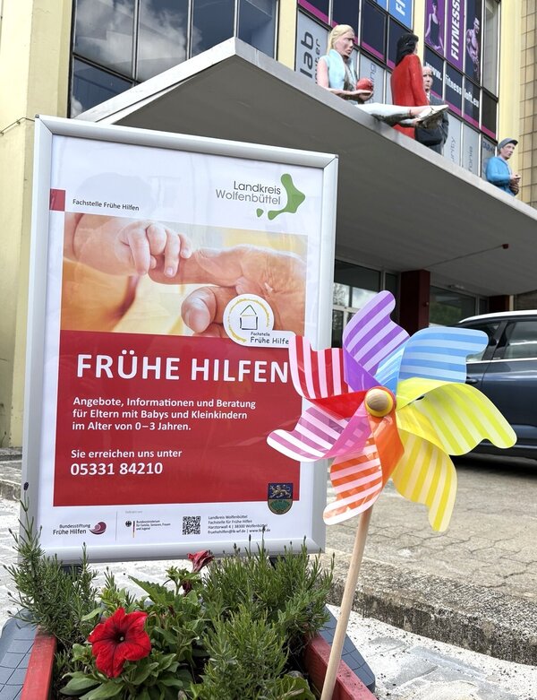 Bunte Windm�hle im Blumenk�bel. Ein Werbeplakat der Fachstelle Fr�he Hilfen. Im Hintergrund die KuBa Halle.