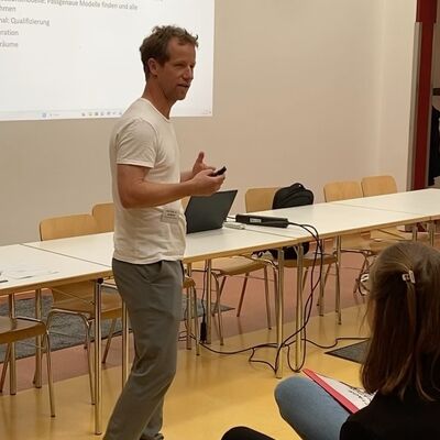 Ein Mann steht vor einer Leinwand und spricht vor Publikum.