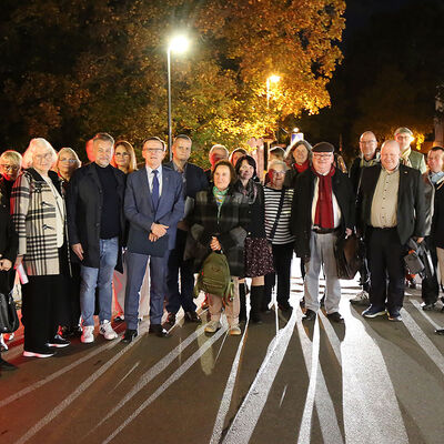 Eine Gruppe von Menschen steht auf einer Br�cke bei Nacht.